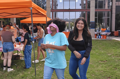 2 students waling in front of an orange pop up tent