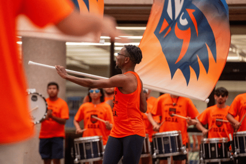 Student conducting and leading the percussion section of the marching band