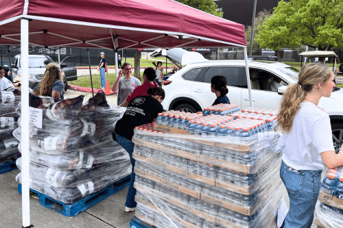 volunteers standing amid pallets of food to give away