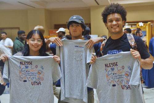 three students holding up Klesse College t-shirts