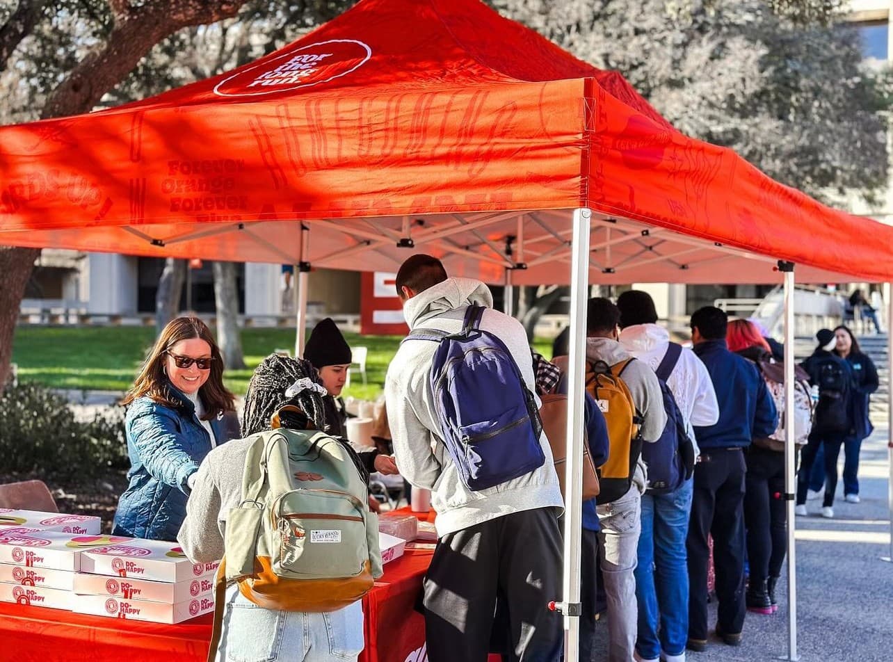students in line in front of an orange tent getting breakfast items
