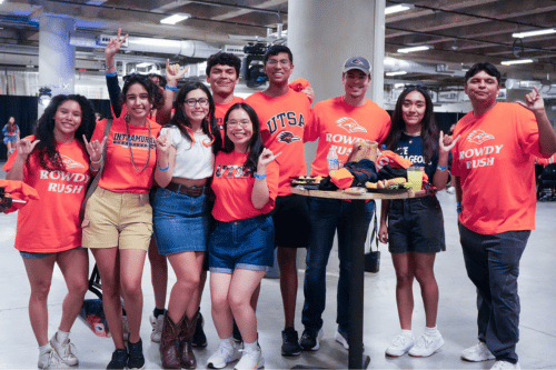 group of people standing around a tall table with snacks and other small items 