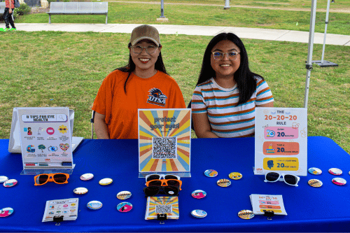 two people sitting at a table with signs and buttons
