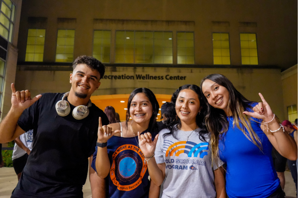 Four students with their Birds Up standing in front of the Campus Recreation Center