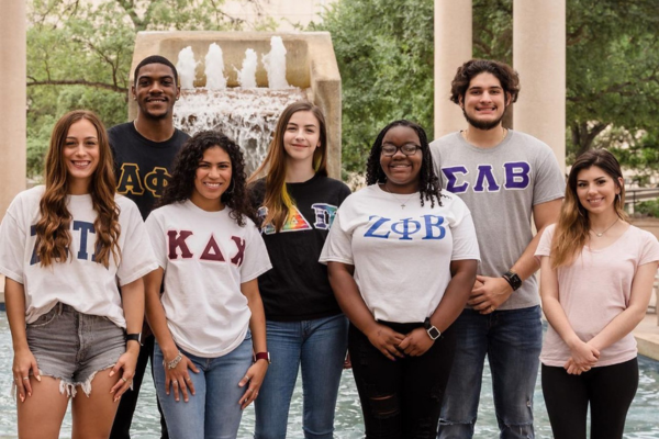 seven students standing in front of the sombrilla fountain representing all four councils
