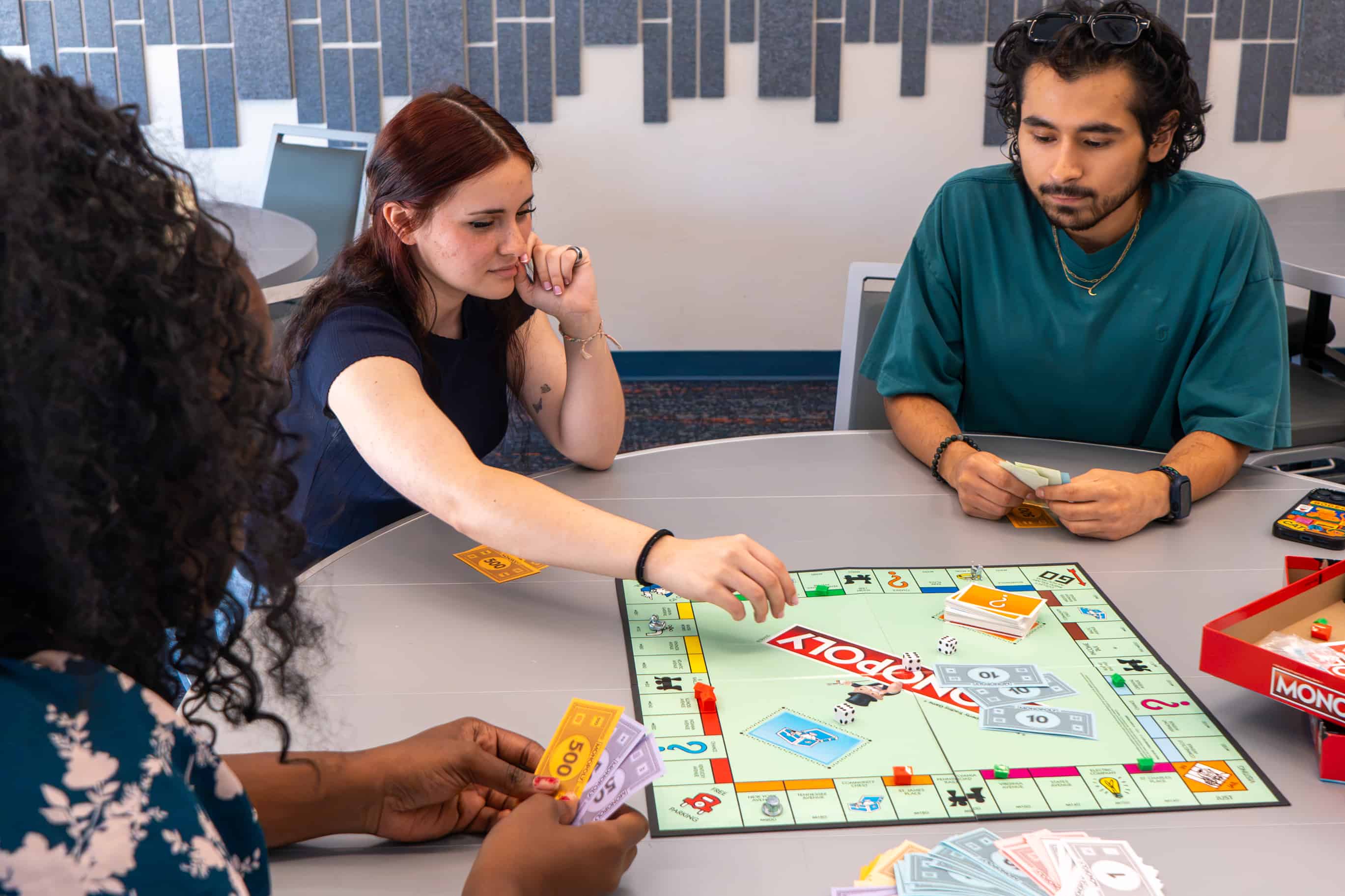 three students playing Monopoly