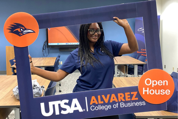 a student holds a large frame that says Alvarez College of Business Open House