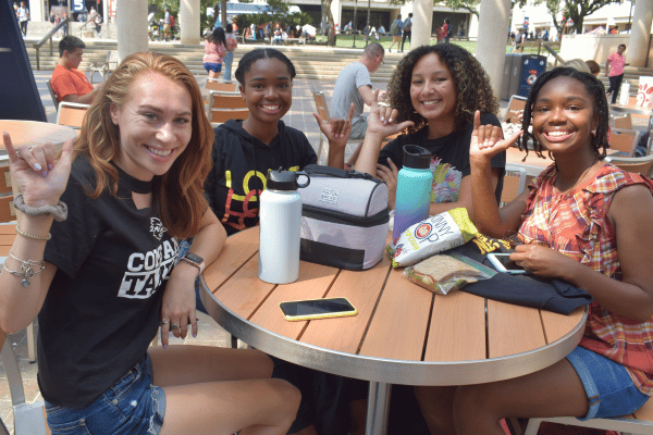 four students sitting at a table in Sombrilla Plaza