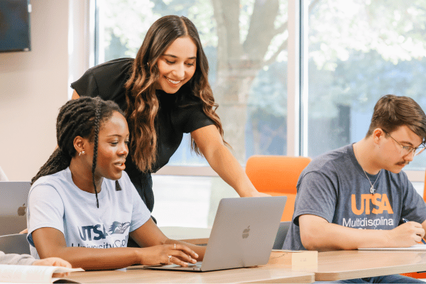 student helping another student on her laptop