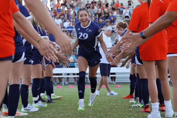 soccer player running through teammate getting low fives