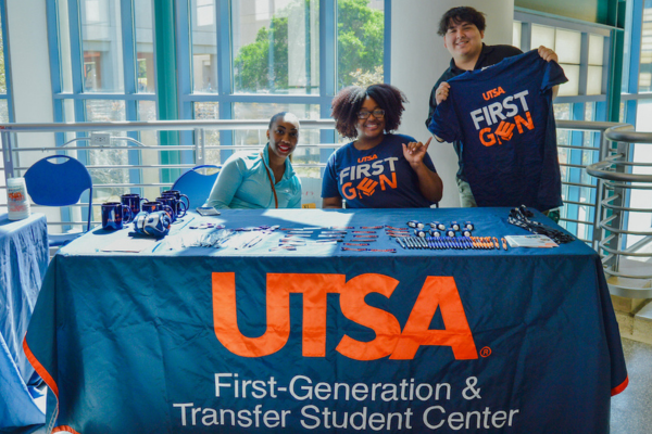 students behind a table with a First Generation and Transfer Student Center banner